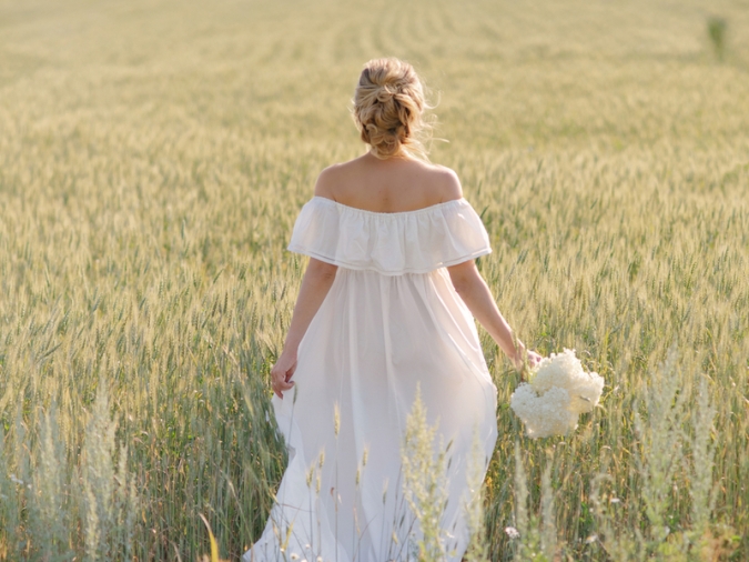 草原に花束を持ちドレスで立つ女性