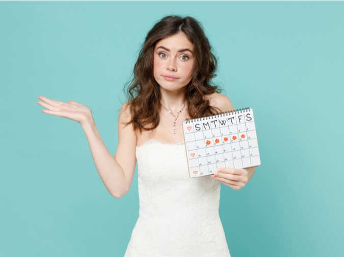 生理周期の書かれたカレンダーを持つ女性