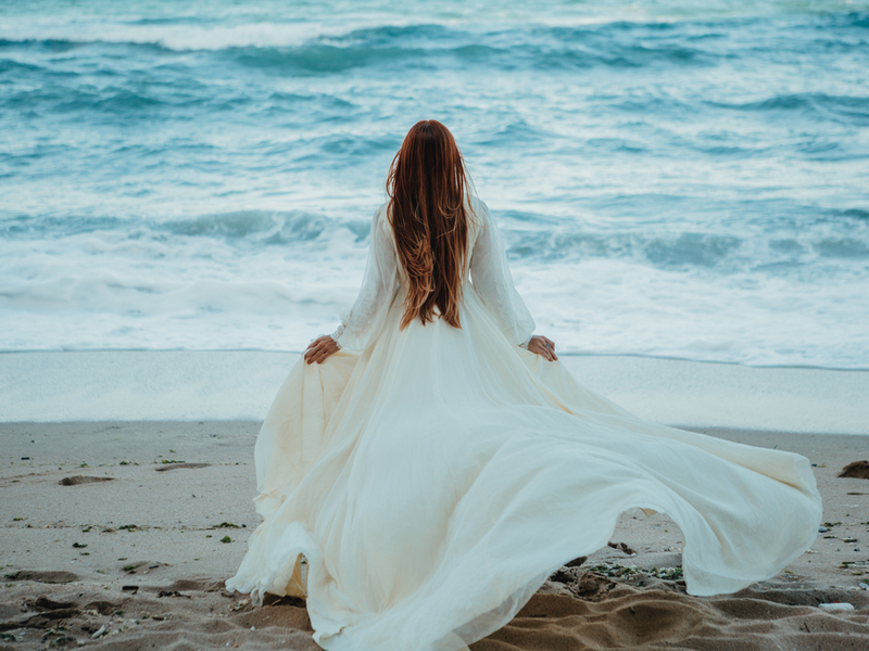 海の前にいるドレスの女性