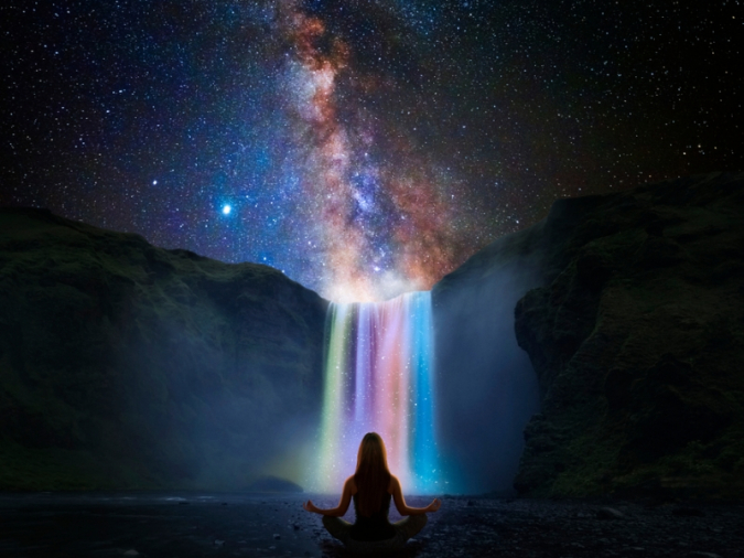 虹色の滝の前で座る女性