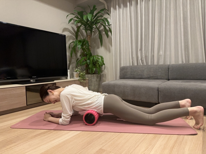 お腹の下にローラーを置いてうつ伏せに。深い呼吸を繰り返してリラックスしながらローラーにお腹を預けて、前後にやさしく転がす。