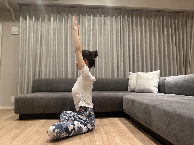 椅子に座り、両腕を天井に向かって伸ばす。